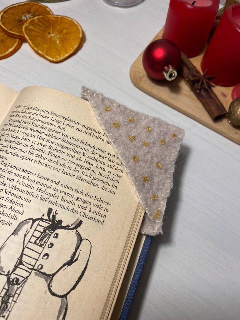 Lesezeichen-Alternative. Eine aus Stoff genähte Leseecke die über die Seitenecke gestülpt wird. Verziert mit goldenen Punkten und sichtbaren Kantennähten